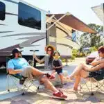 Family relaxing in camping chairs at the campsite spending time together on vacation in modern rv park